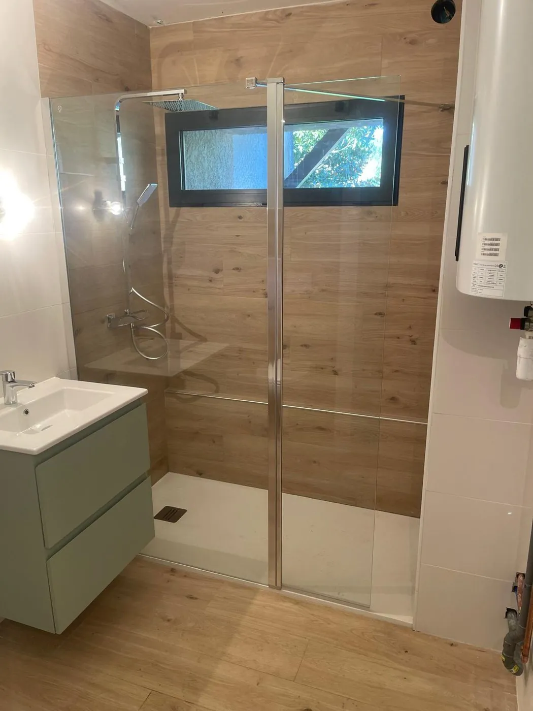 Après travaux — Salle de bains des années 70 entièrement rénovée : douche à l'italienne effet bois, meuble vasque vert sauge.