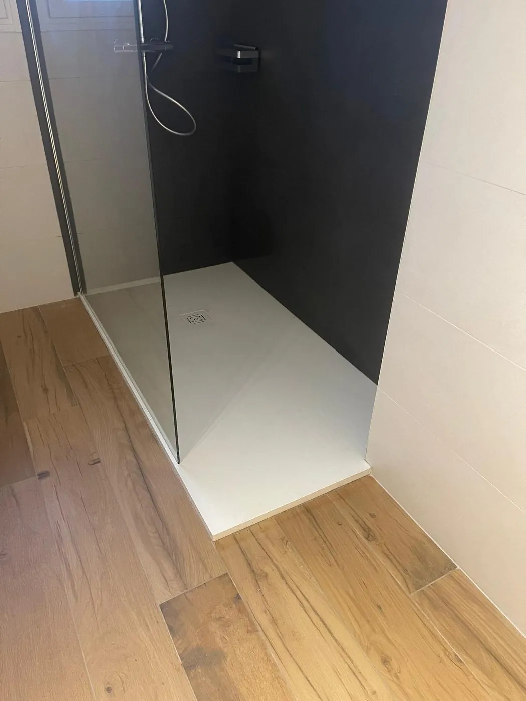 Après travaux — Contraste noir mat et sol grès cérame effet parquet : douche à l'italienne extra-plate créée après démolition complète.