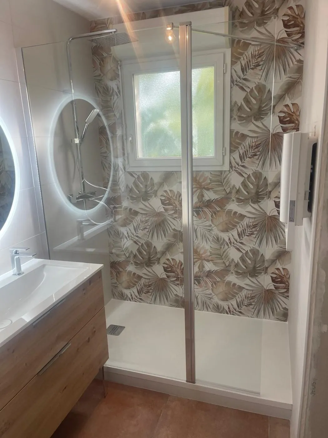 Après travaux — Rénovation complète : dépose de la baignoire, douche à l'italienne, faïence décor végétal, meuble et sol grès cérame terracotta.