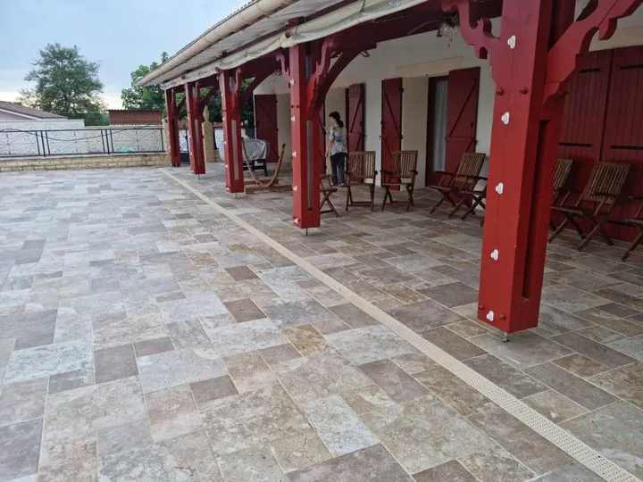 Terrasse couverte en travertin sous l'auvent en bois