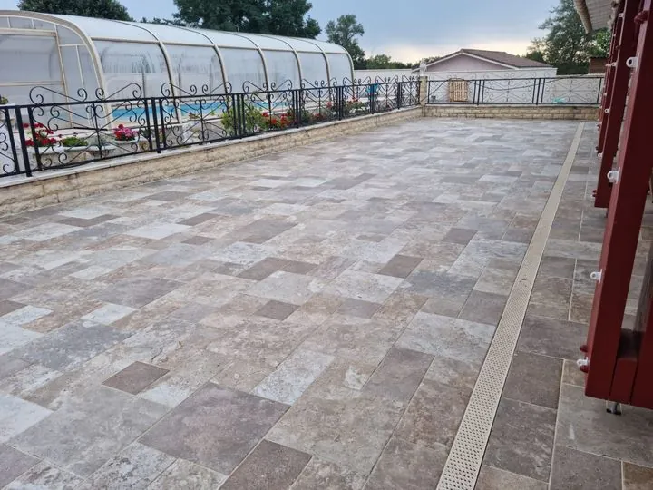 Grande terrasse en travertin le long de la piscine couverte